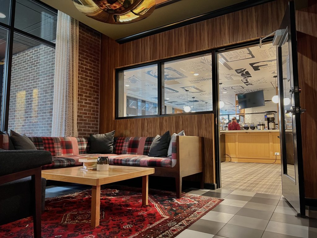A warmly furnished sitting area is next to the open door to a fun-looking coffee shop. Located in the lobby of the Graduate Hotel in Columbus, Ohio.