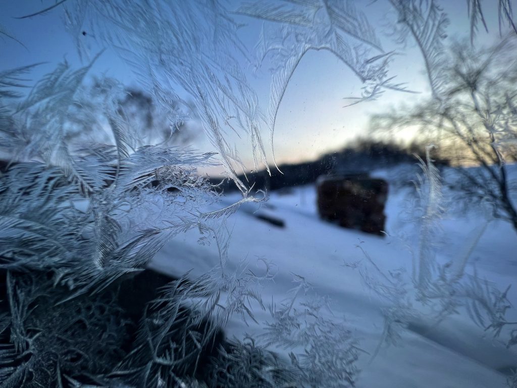 Frost forms unique patterns on a window that overlooks a snow-covered roof in rural Wisconsin.